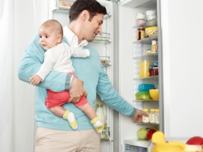 папа с ребенком вынимает бутылочки с грудным молоком из холодильника